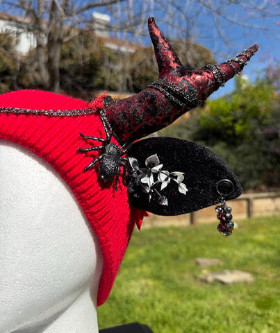 Bright red beanie with black &amp; red metallic textured antlers. A black spider perches from either side near sprouting black-to-white ombre ferns. Slim furred black ears have rhinestone earrings that dangle with a shine.