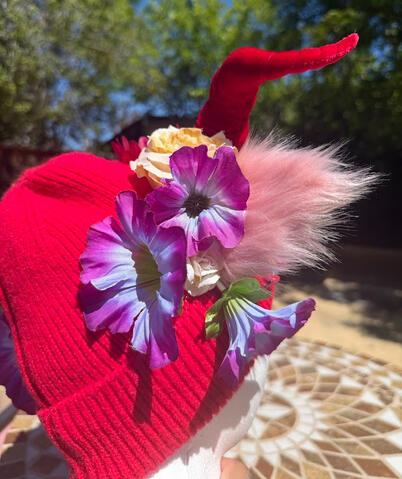 A random and colorful selection of faux flowers decorate the base of the horns and back of the beanie. Not completely symmetrical but balanced in splashes of color!