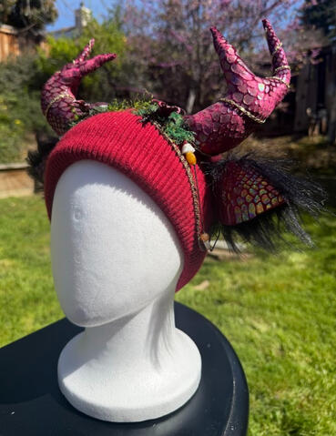 Surrounded by moss, a maroon stag beetle perches on top of the beanie. This is perfect for your scale / reptilian / entomology / bug lovers! Antlers are poseable, ears are pierceable &amp; bendable. Beanie has inner lining of furred black plush material.