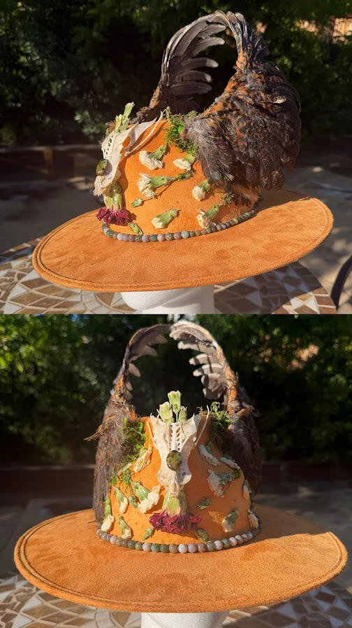 Slightly muted tangerine orange hat with tall oval shaped top. Framed by beautiful bold chicken wings sourced from JAKRabbitry on Etsy. Bird sternum bone with quail stone displayed front and center, surrounded by dried pressed carnations.