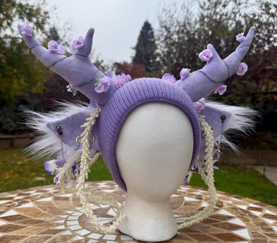 Light lavender (unlined) beanie with velvet lavender antlers. Ears feature 2 mini silver gauges with fluffy white furred backing. A silver and plum beaded chain flows through the gauges on each ear.