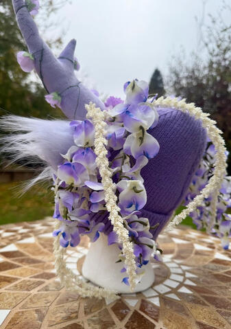 White floral vines and white-purple/blue wisteria strands line either side of the beanie.