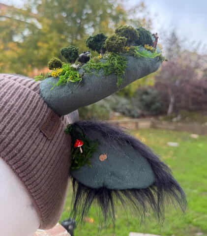 Small metal charms accent each inner ear. A family of deer can be spotted along the forest line along with a black bear and moose.