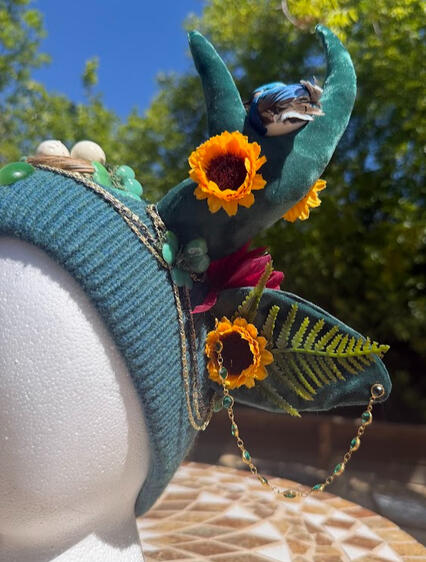 This beanie has gold & emerald jewelry accents as well as brass chains framing the front and sides of the beanie.